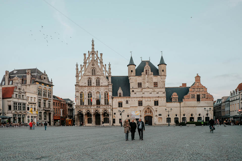 [Alt-teksi: tori, jossa kävelee muutamia ihmisiä. Taustalla Mechelenin koristeellinen kaupungintalo.]