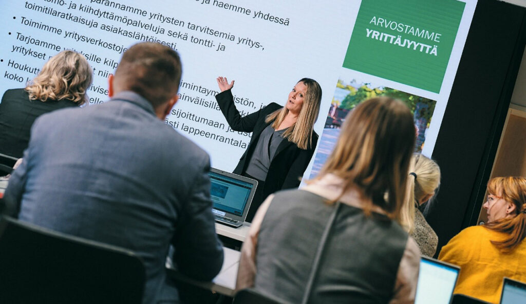 [Alt-teksti: henkilö pitämässä esitystä luentosalissa, taustalla teksti arvostamme yrittäjyyttä.]