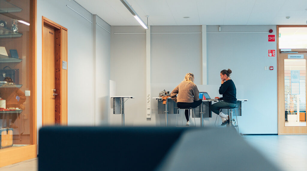[Alt-teksti: Kaksi opiskelijaa työskentelee tietokoneilla luokkatilassa.]