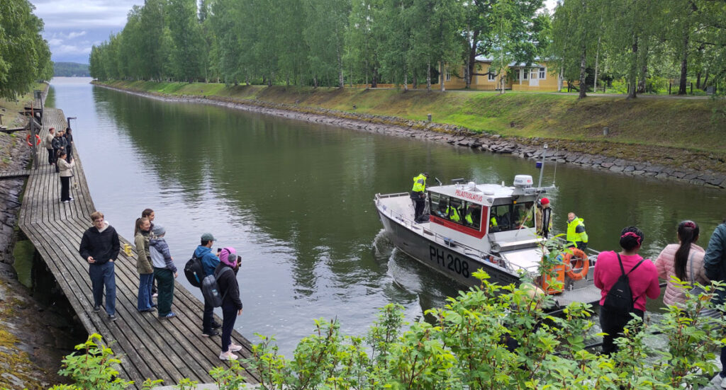 Kanavan laiturilla ihmisiä ja vene kanavalla.