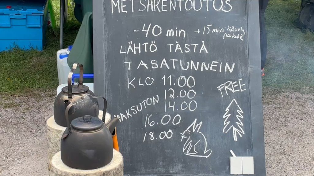 [Alt-teksti: ulkona oleva liitutaulu ja sen vieressä kaksi nokista kahvipannua kantojen nokassa, taulussa lukee metsärentoutus, maksuton, lähtö tästä tasatunnein sekä kellonaikoja.]
